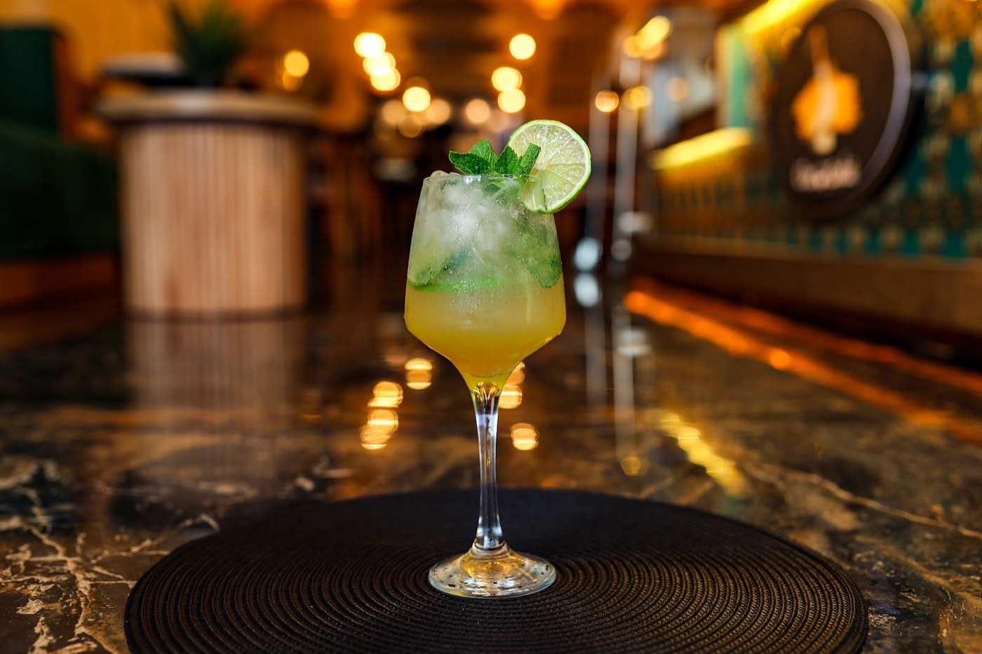 A fresh lime-and-mint mocktail on a marble table at Chai Kadai, warm bar lights behind