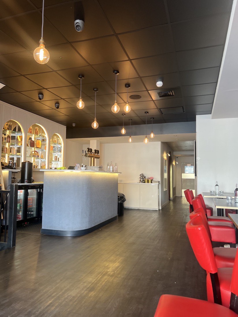 Inside Chai Kadai East Ham — warm Edison-bulb lighting, an arched display bar and dining seating